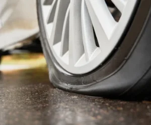 stopped-white-car-with-punctured-tire-roadside